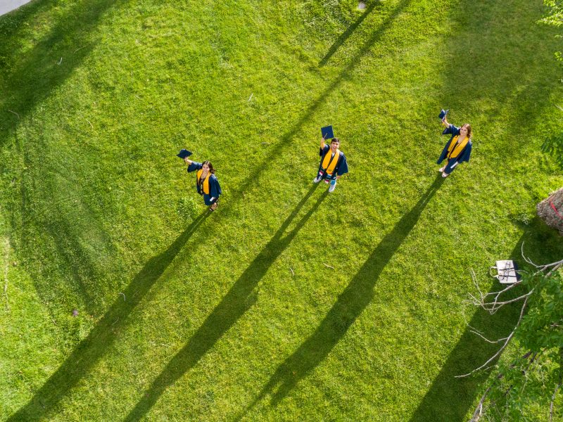Students on field wearing cap and gown.
