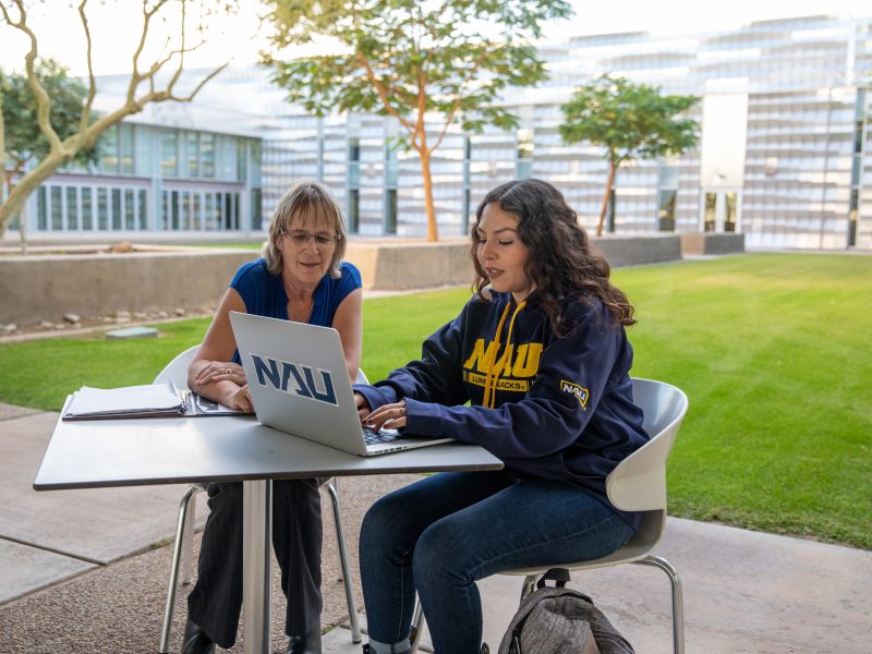 Advisor helping student on laptop.