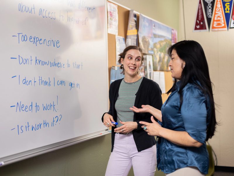 Students discussing topics on a whiteboard.