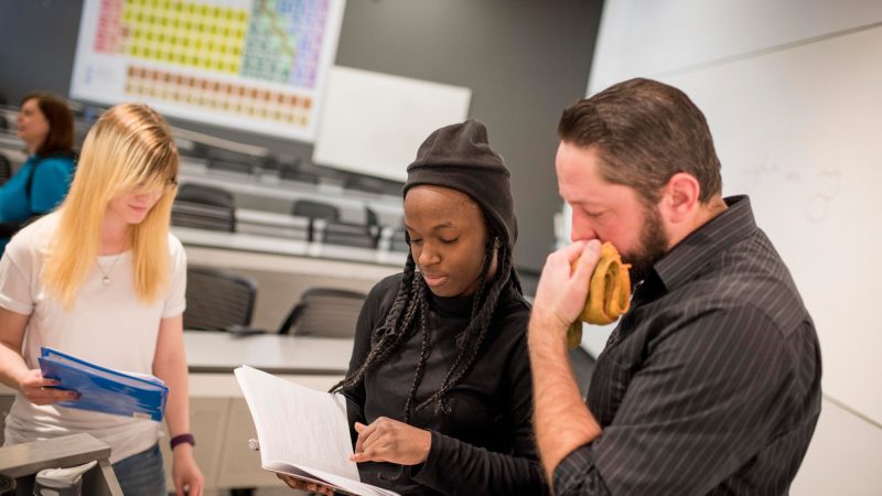 N A U student speaking with professor in classroom.