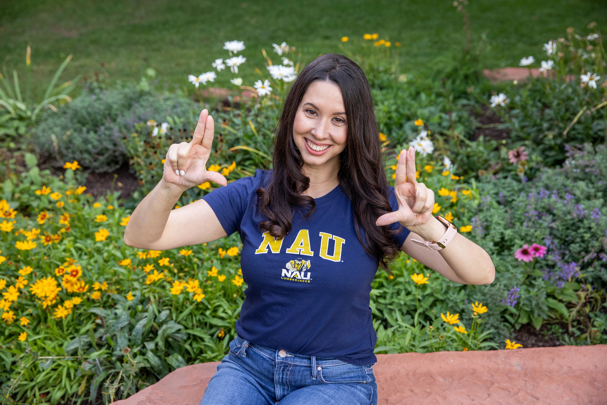N A U alumni smiling and holding up the axe up sign at the camera.