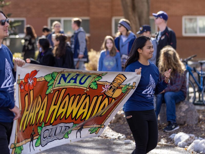 N A U students marching in parade with a banner that says Hapa Hawaiian Club.