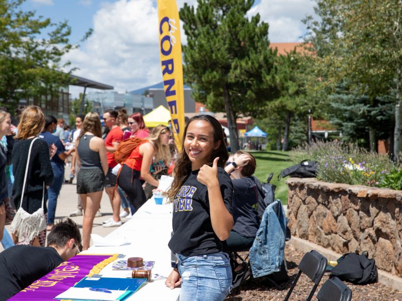 N A U student smiling and giving a thumbs up during a club fair.