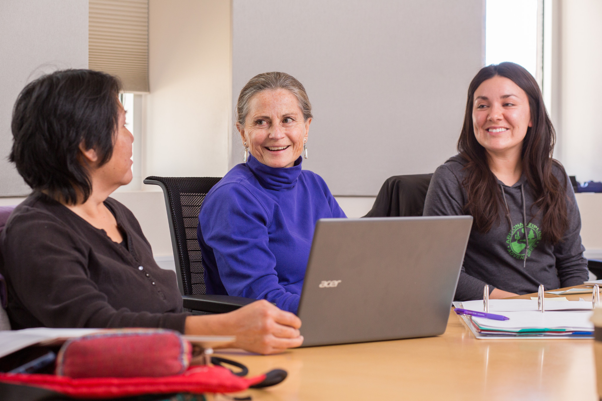 Faculty speaking with each other on table.