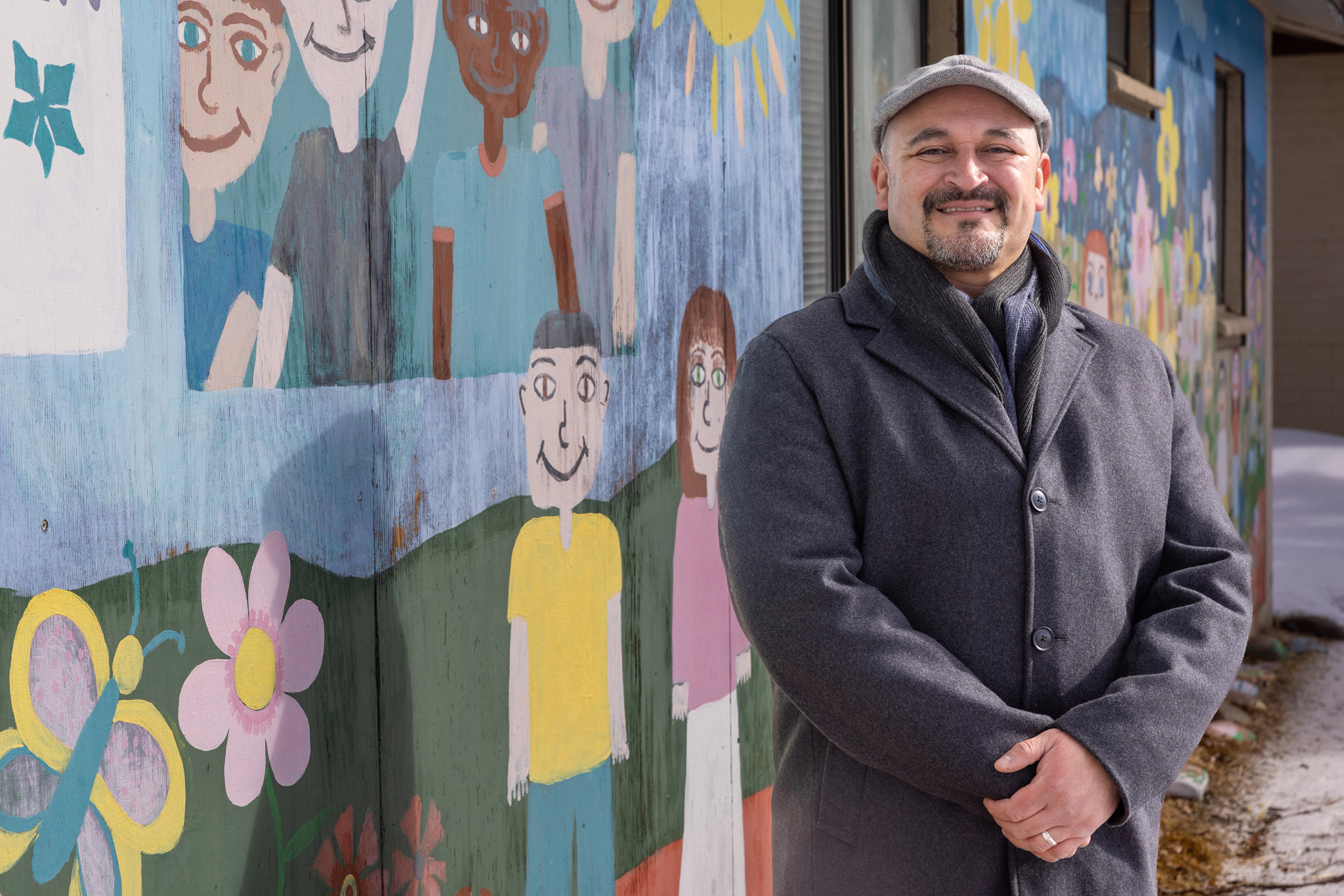 Alumni smiling posing in front of the camera with artwork in the background.