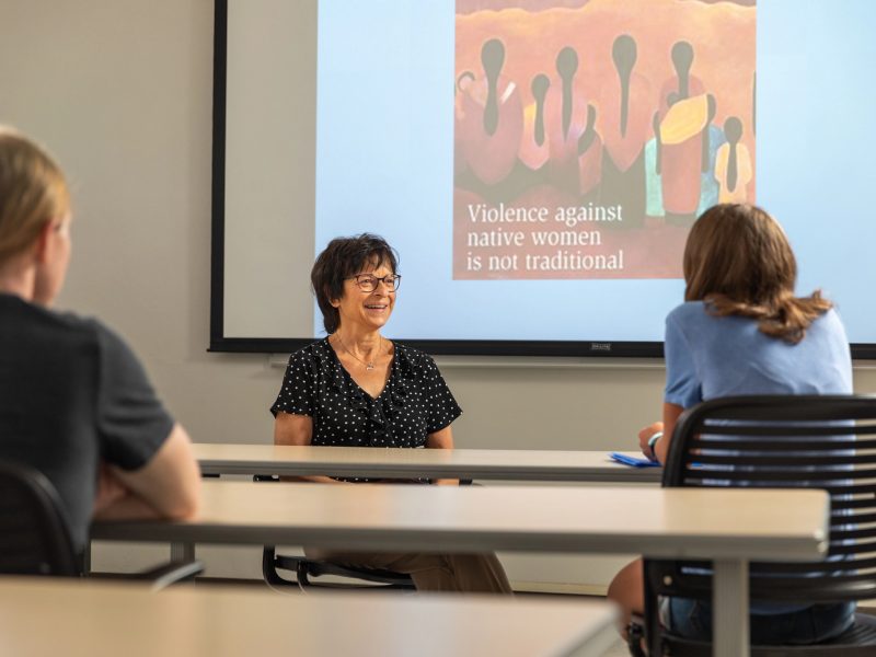 Professor and student speaking with each other in a classroom environment.