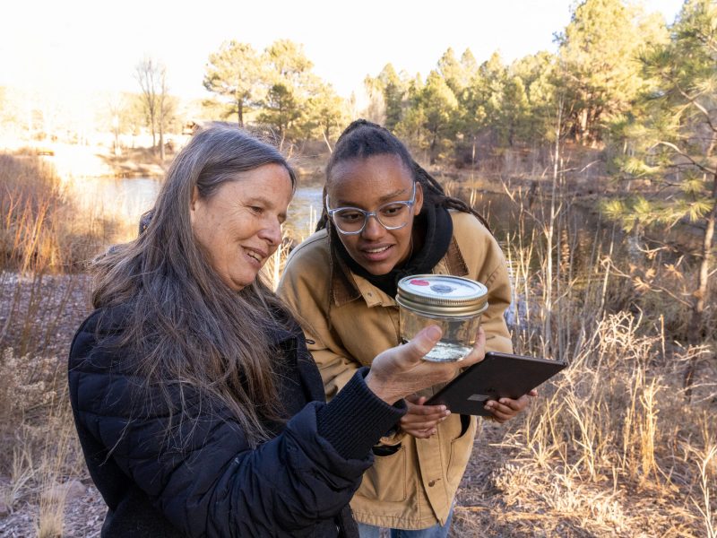 N A U students looking through a sample jar outdoors.