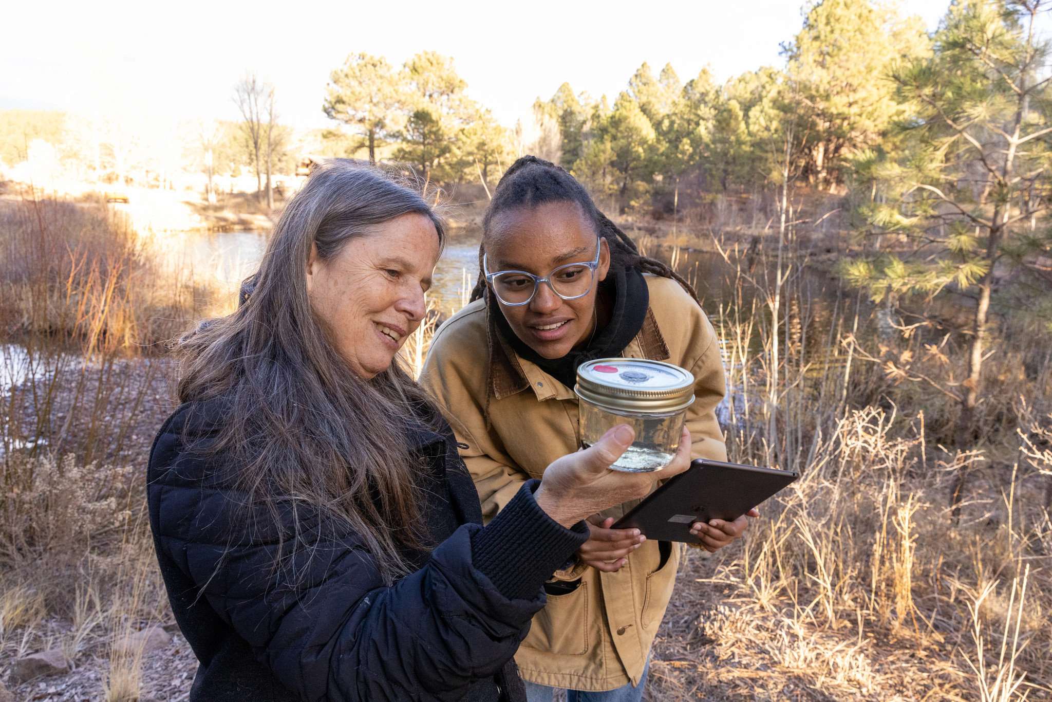 N A U students looking through a sample jar outdoors.