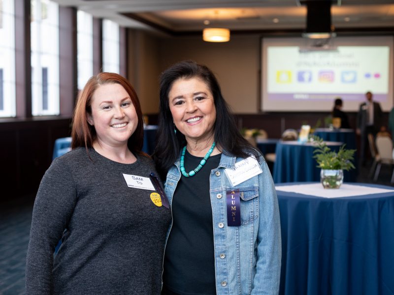 N A U alumni smiling at the camera in a reunion setting.