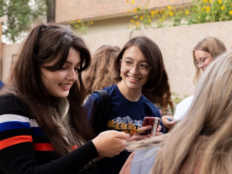 N A U students smiling while holding a butterfly outdoors in a lab.