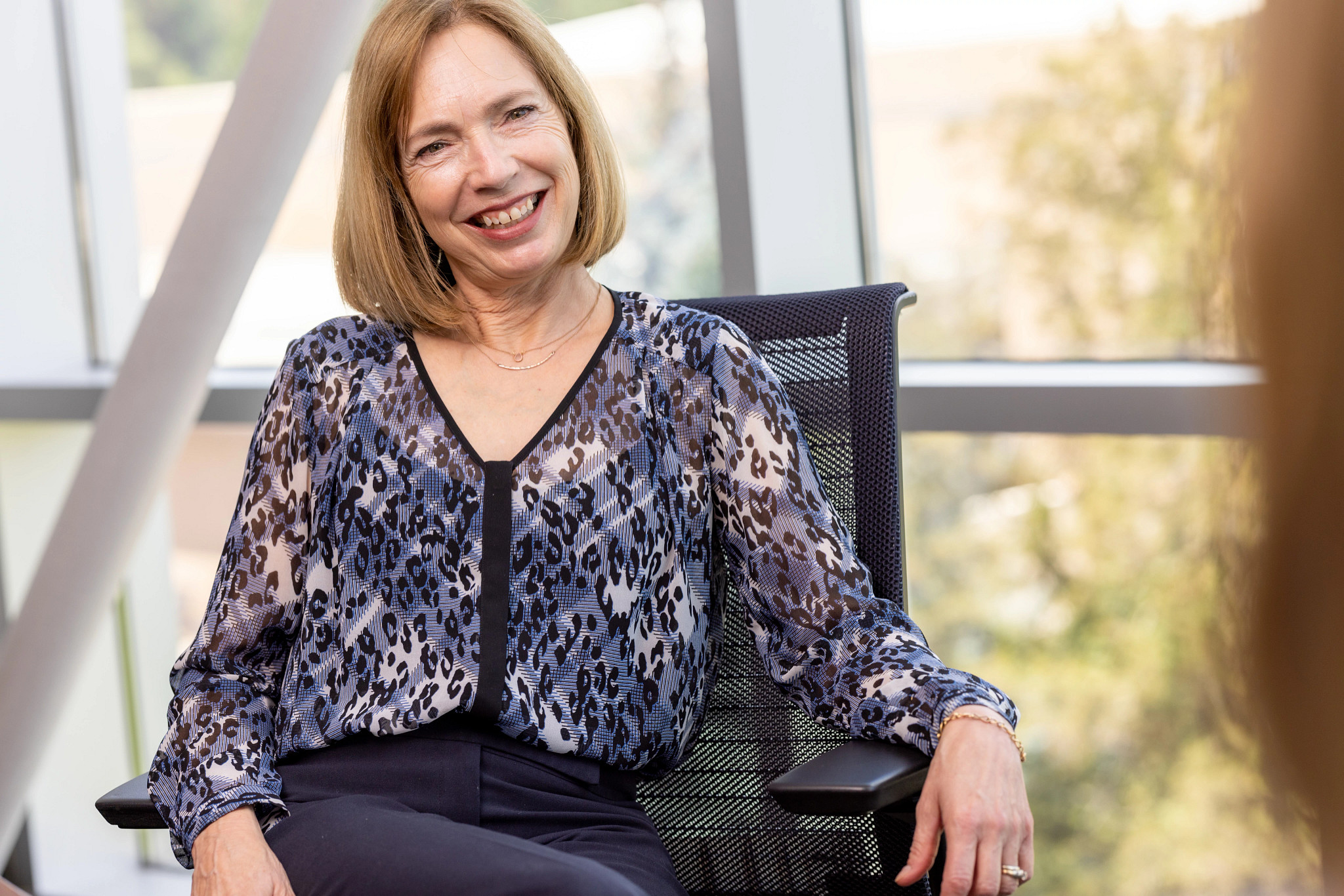 Faculty member smiling at the camera in a meeting room environment.