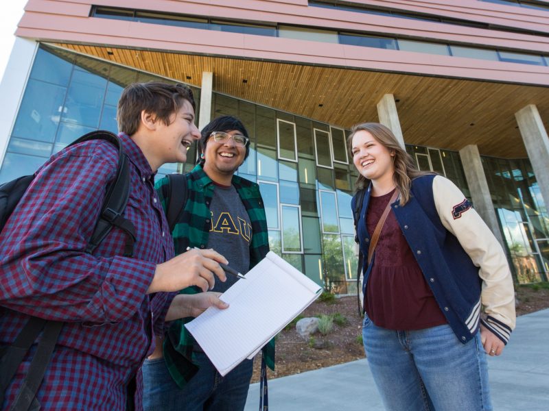 Students smiling at each other outside.