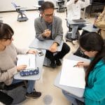 Faculty member and students collaborating in the classroom.