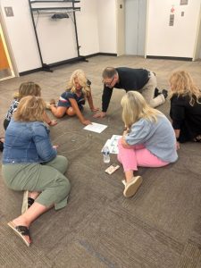 Group of people sitting in a circle on the floor of a conference room playing a game