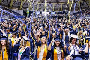 A group of NAU graduates cheering in a stadium with confetti