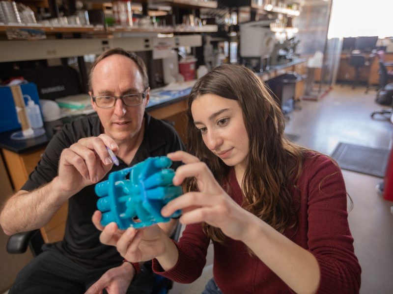 Professor and student working on invention in lab.