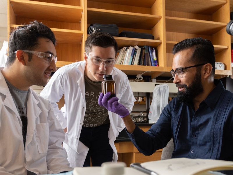 Researcher and students inspecting glass container.