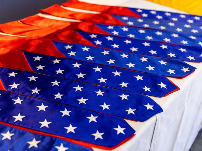 Row of veteran graduation stoles places next to each other on a table.