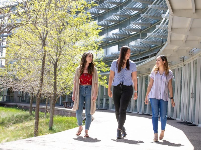 Three graduate students walking outside the Applied Research and Development building on a sunny day.