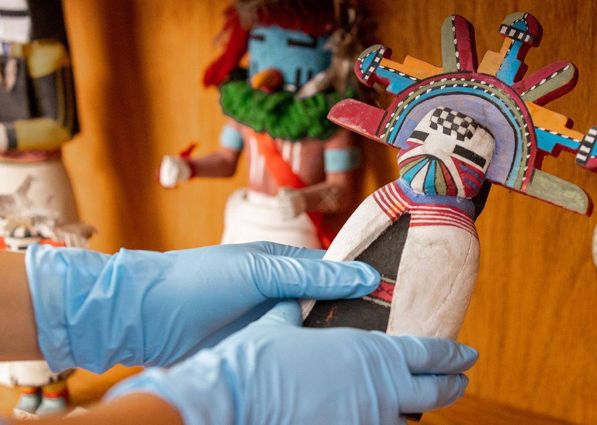 A close up of a Kachina doll with a human-like body, wearing colorful robes and a colorful headdress.