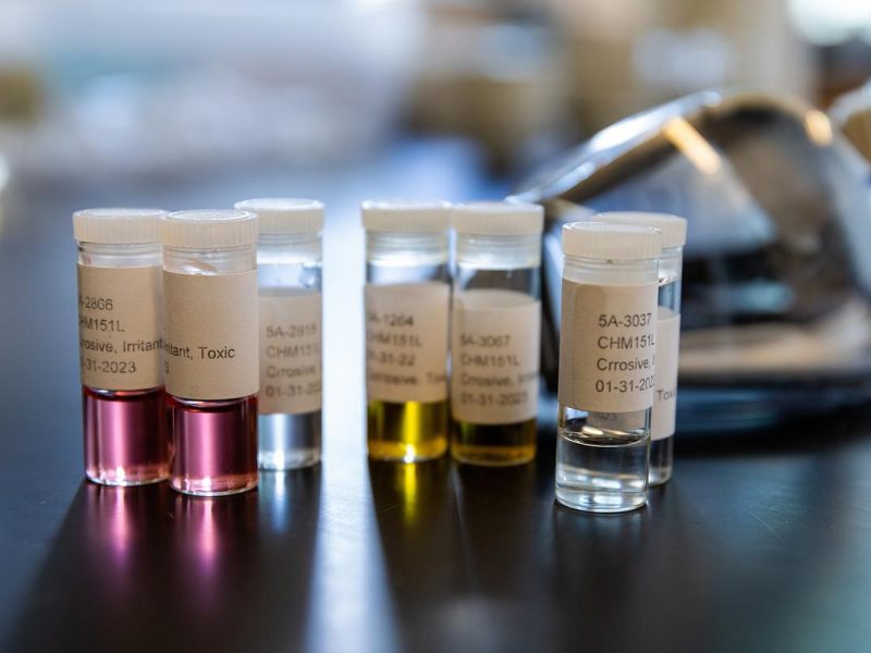 Different colored vials with labeling sitting on a counter in a research lab.