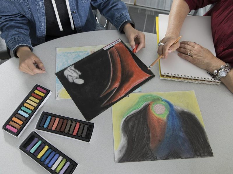 Drawings and colorful chalk placed on a table.