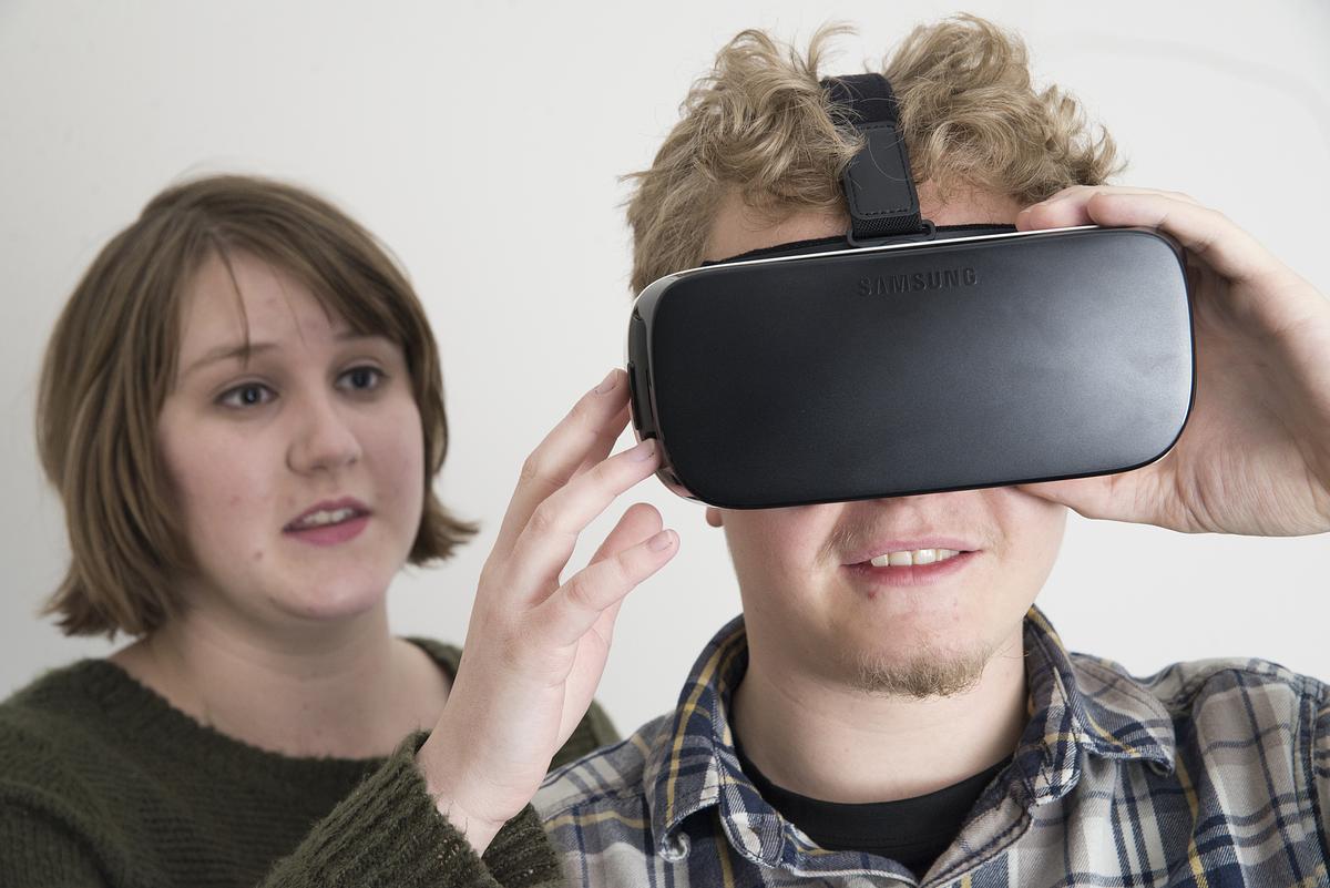 Person placing visual reality googles on a person.