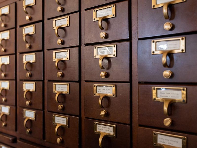 Rows of wooden drawers with metal labels, front view on a library catalog.