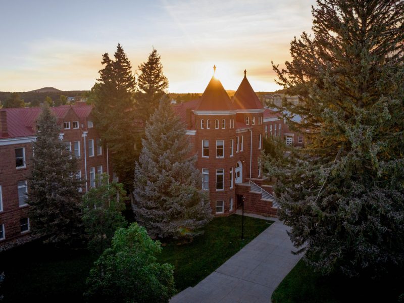 NAU campus setting with brick buildings, trees, and a paved walkway at sunset.