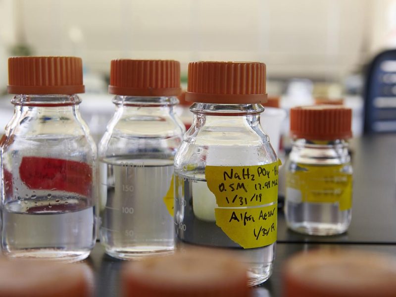 Glass bottles with red caps, yellow labels, and various measurements and chemical notations.