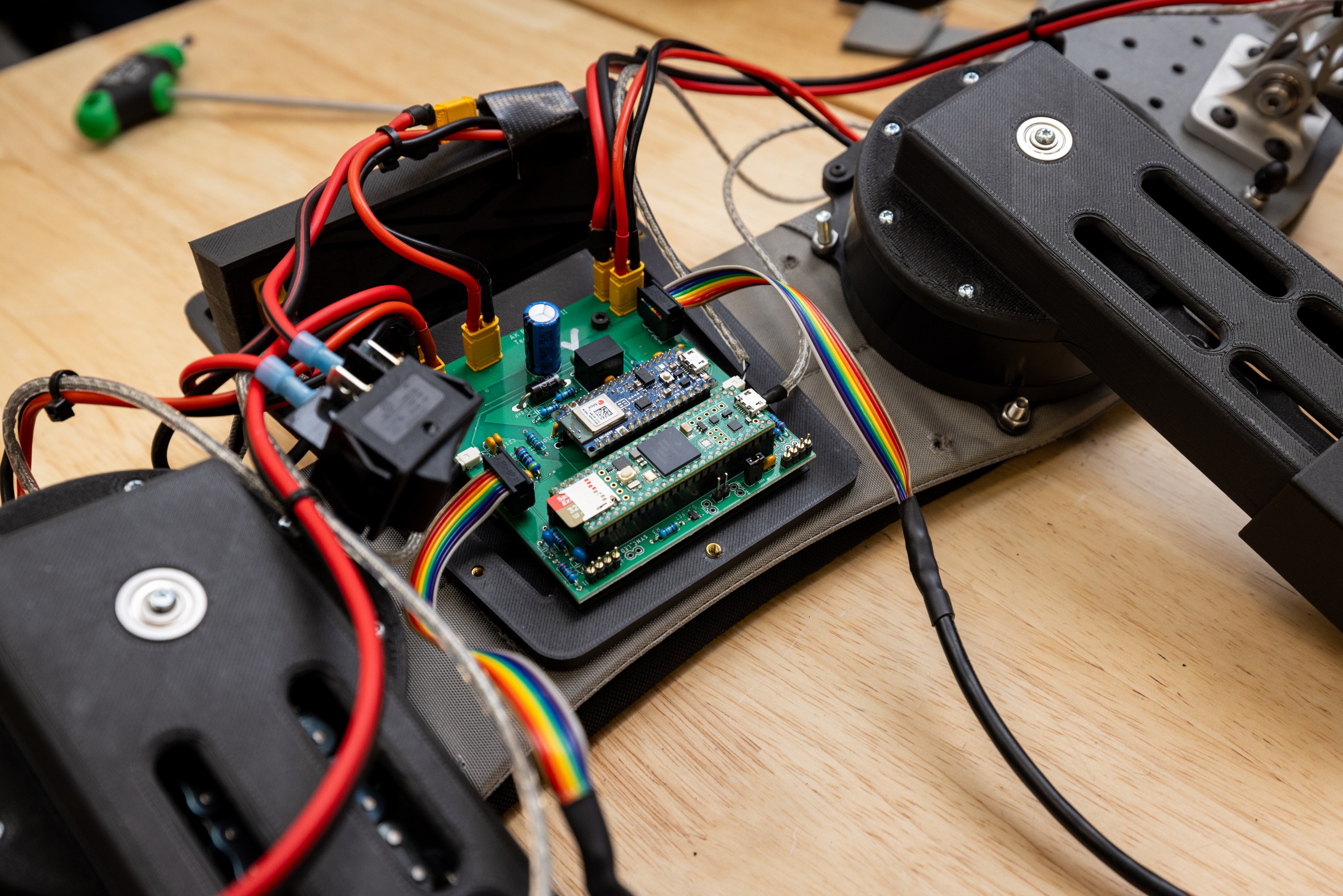 Electronic components, circuit board, wires, motors, electronic devices on a wooden surface.