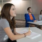 Student writing and listening to a speaker.