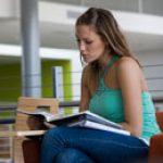 Student sitting in a chair reading a book.