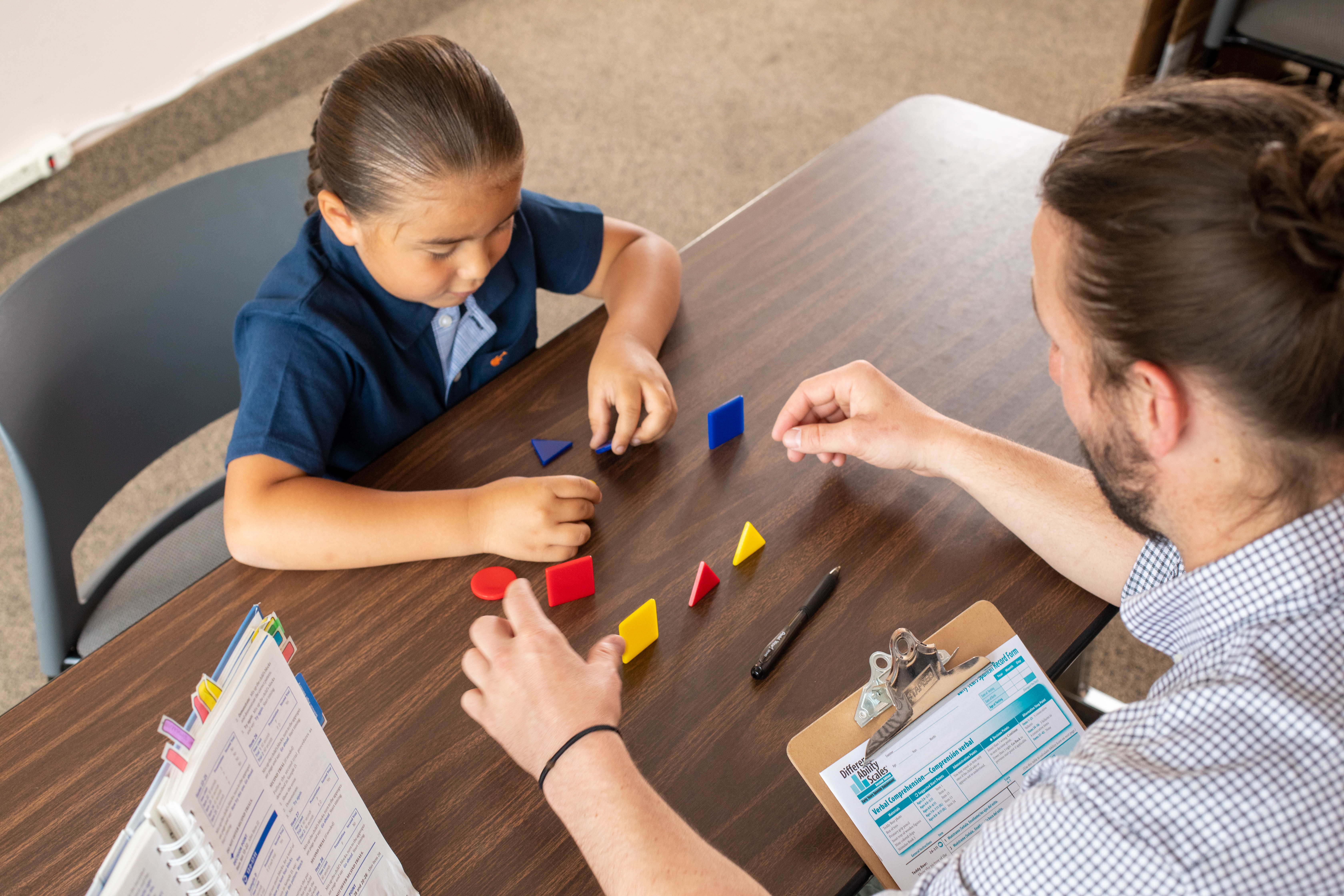 Young student sitting at table working on a activity with counselor.