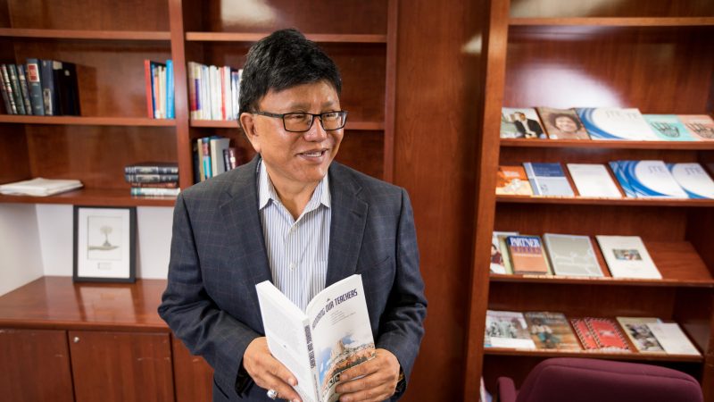Professor Joseph Martin standing in a room, holding a book.