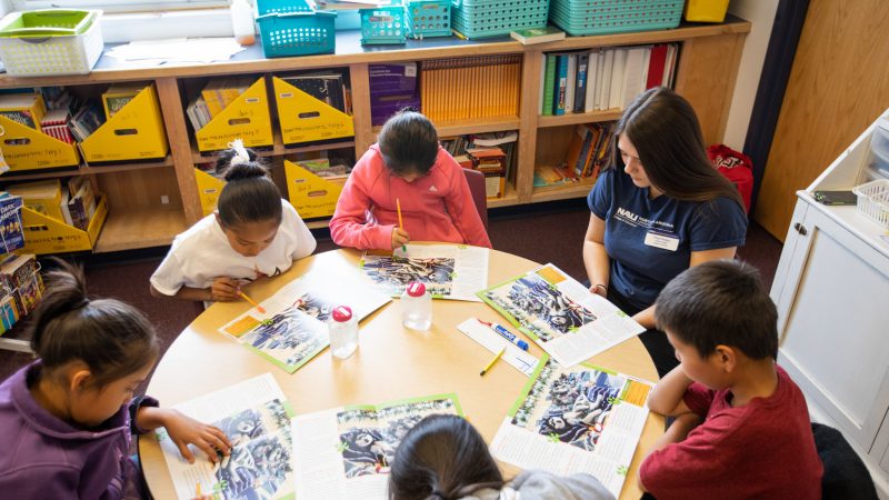 Student teacher sitting at a table with students.