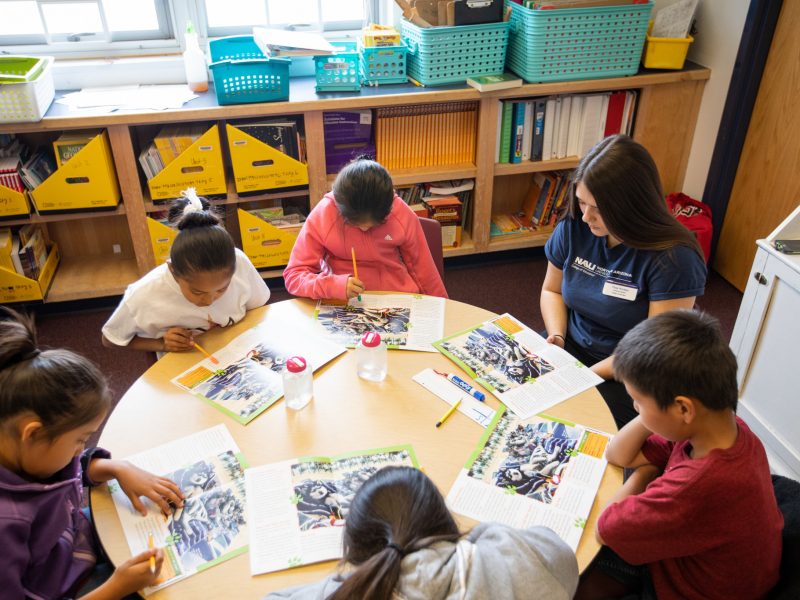 Student teacher sitting at a table with students.