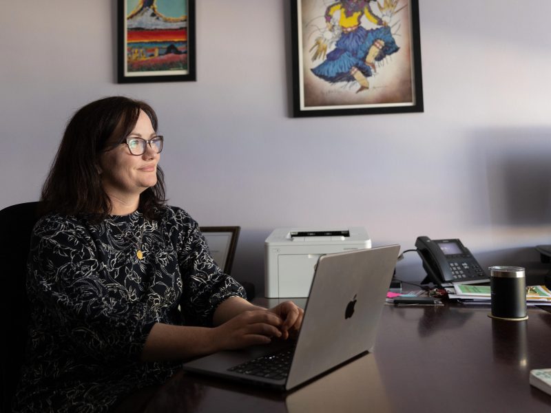 N A U professor sitting at desk and working on laptop.