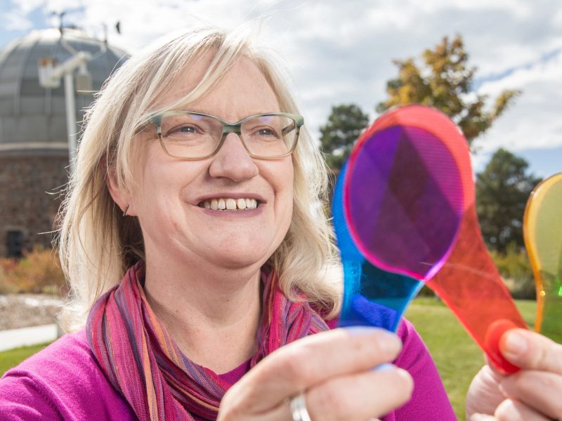 Marti Canipe holding colorful items and looking at them.