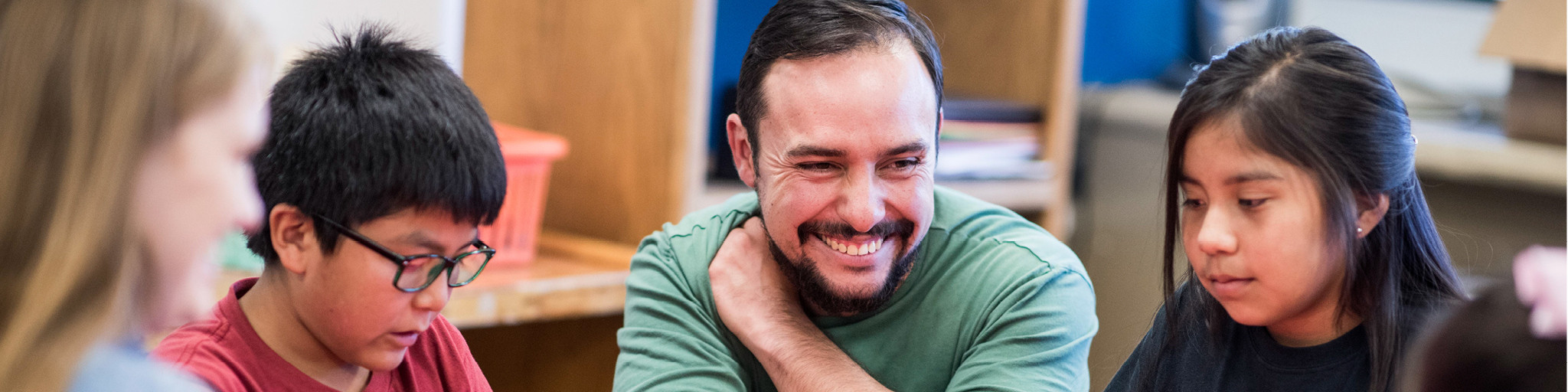 Student teacher works with children at a table.