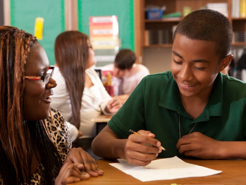 Student teacher helps student with writing assignment.