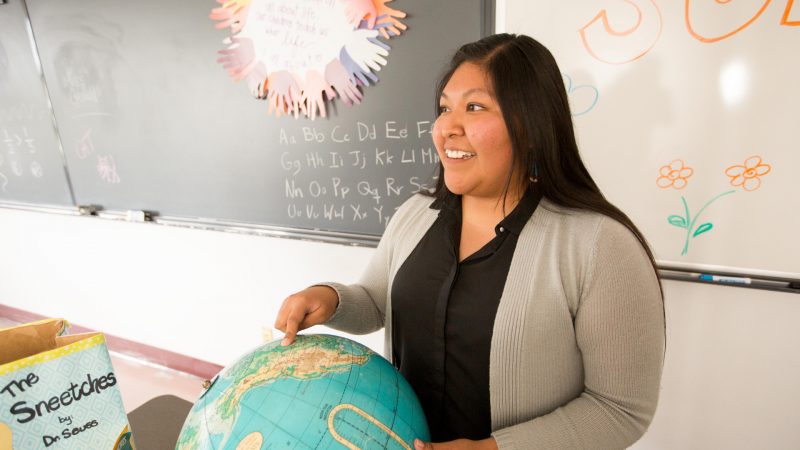 Student teacher points to globe in class.