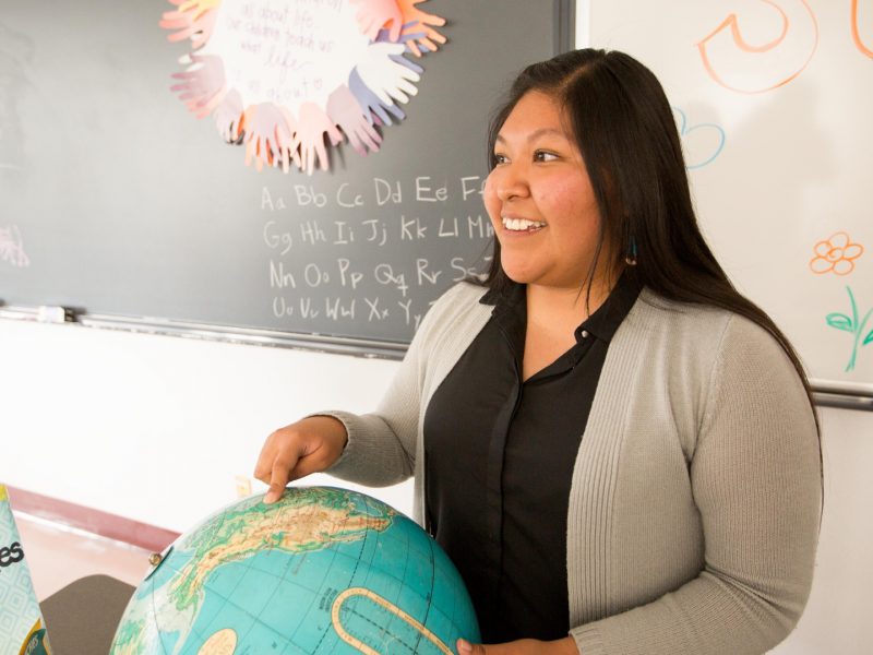 Student teacher points to globe in class.