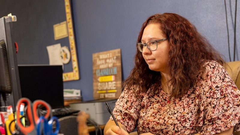 Student teacher writing on a stack of post-it notes.