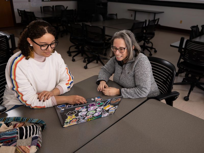 Professor helping student on laptop.