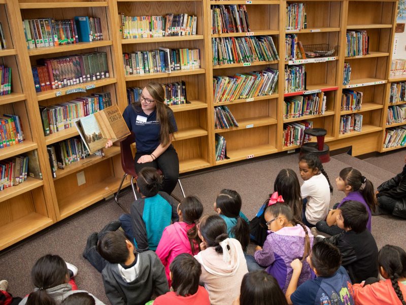 N A U student reading a book to a class.