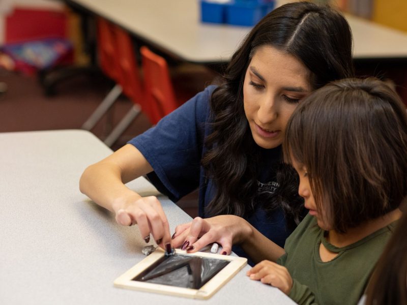 N A U student teacher helps child with project.