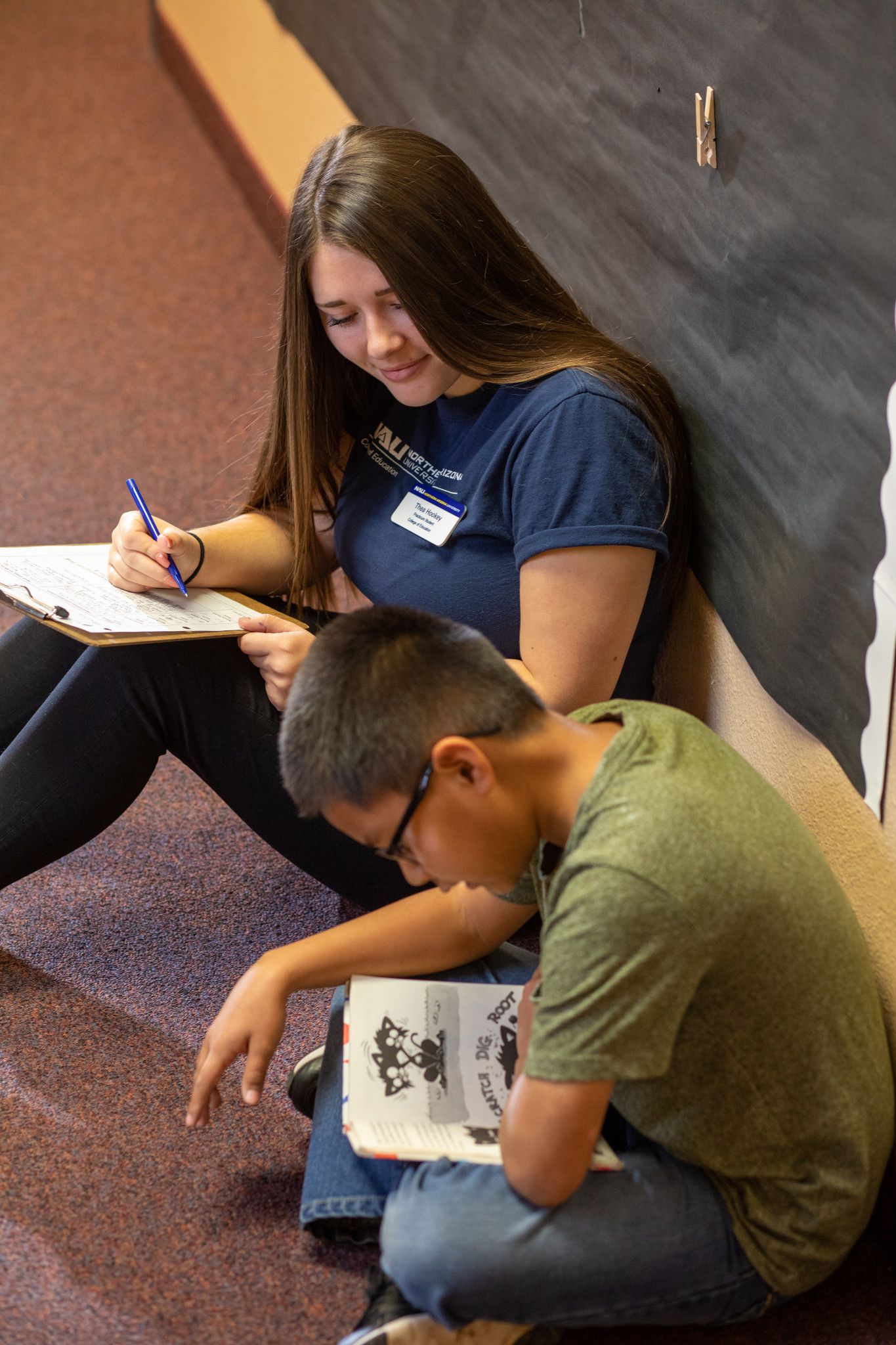 N A U student teacher helps child with learning to write.