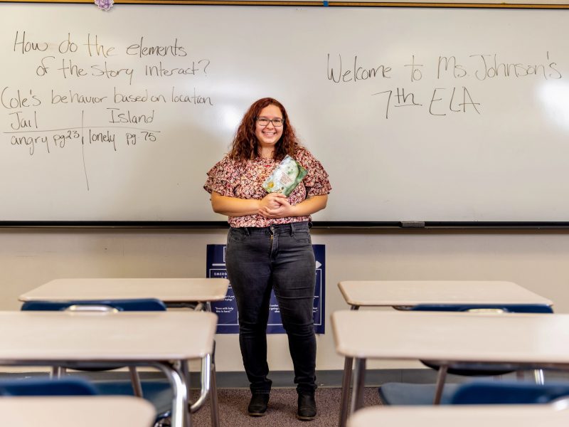 N A U student teacher standing in front of classroom with a book in hand.