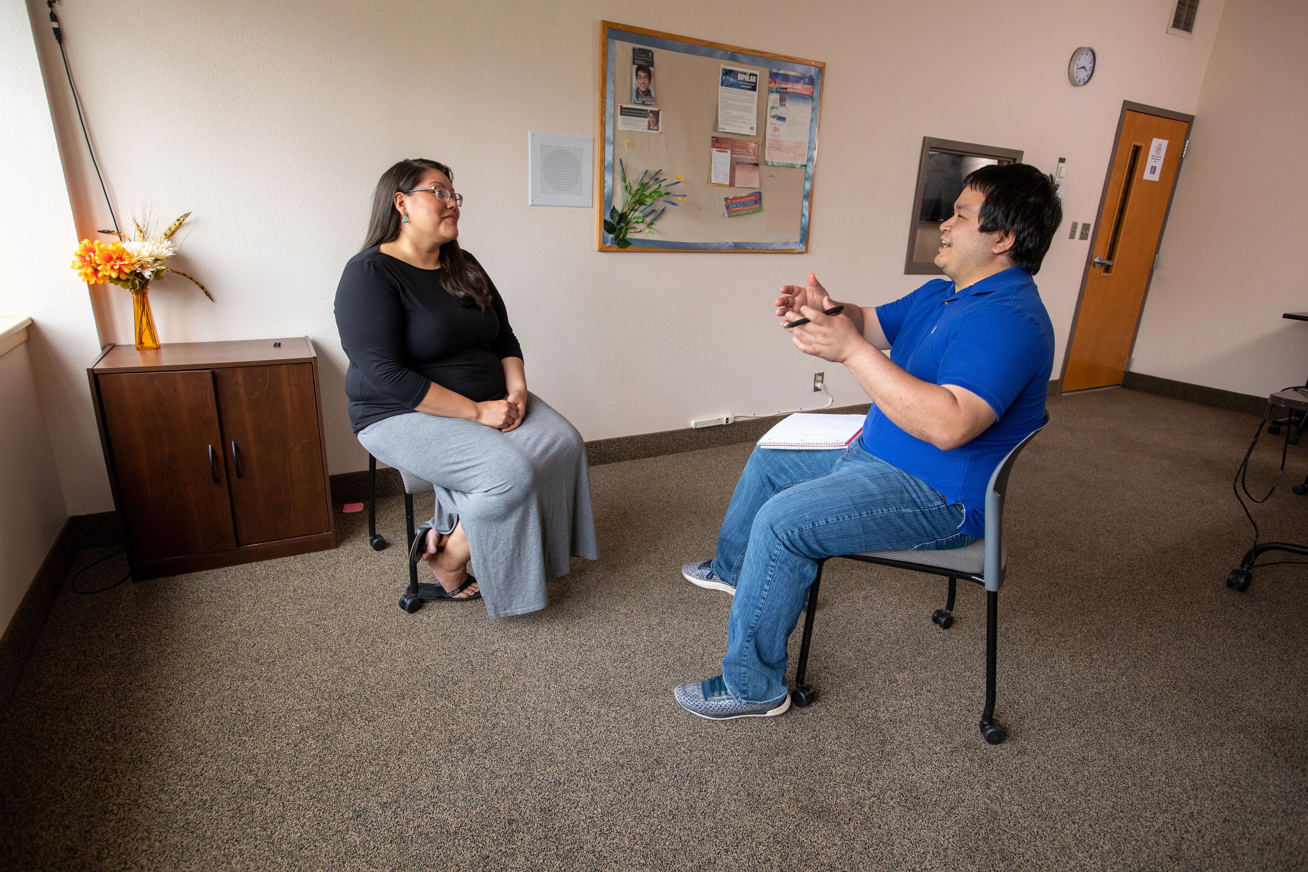 Two people sitting and taking in a closed room.
